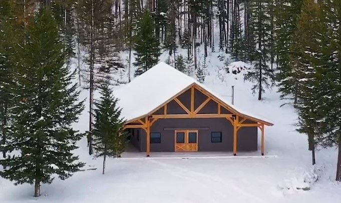 An aerial view of a house in the middle of a snowy forest