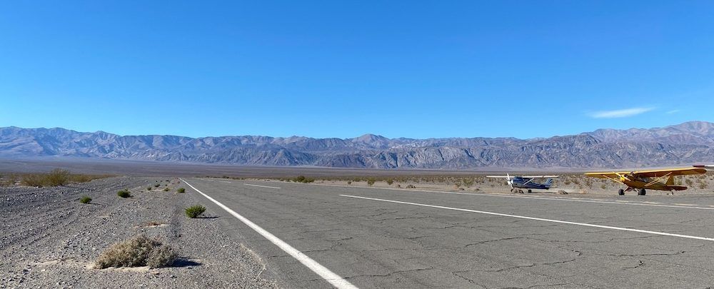 A plane is parked on the side of the road in the desert.