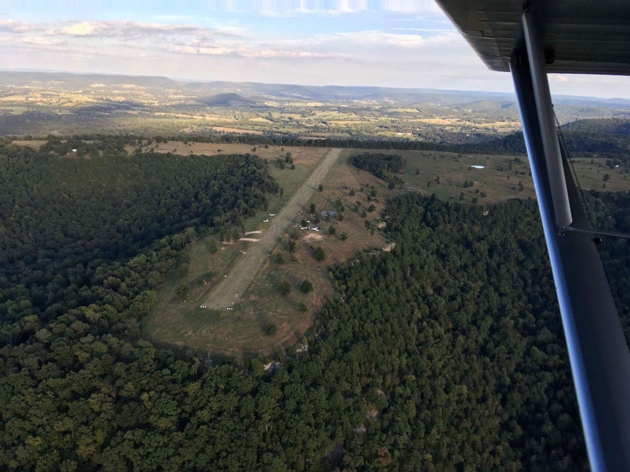 An aerial view of a runway in the middle of a forest.