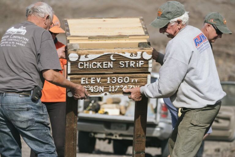 A group of men holding a sign that says chicken strip