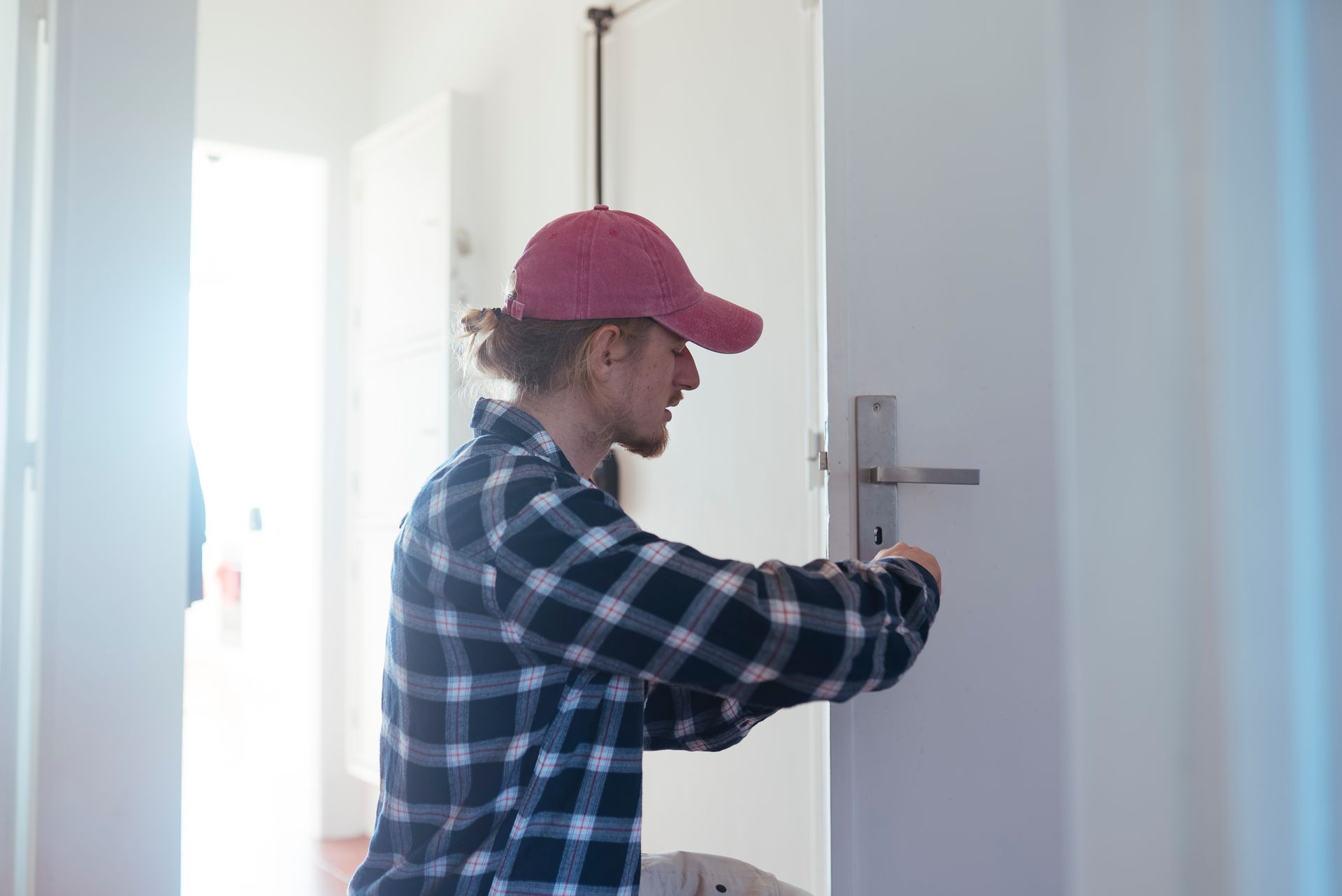 A residential locksmith installing or adjusting a door lock inside a home.