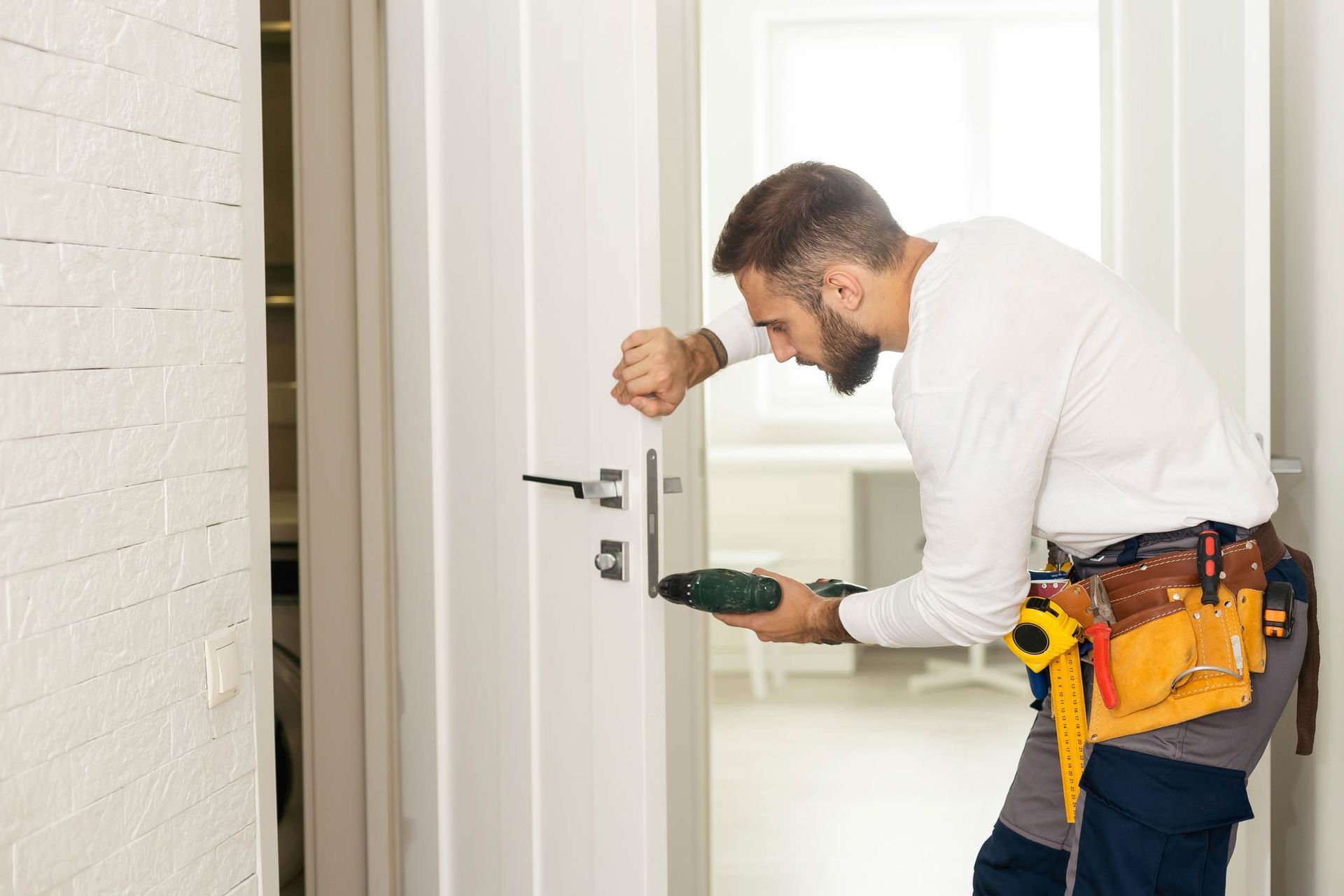 Man providing locksmith services by fixing a door lock in a house entrance