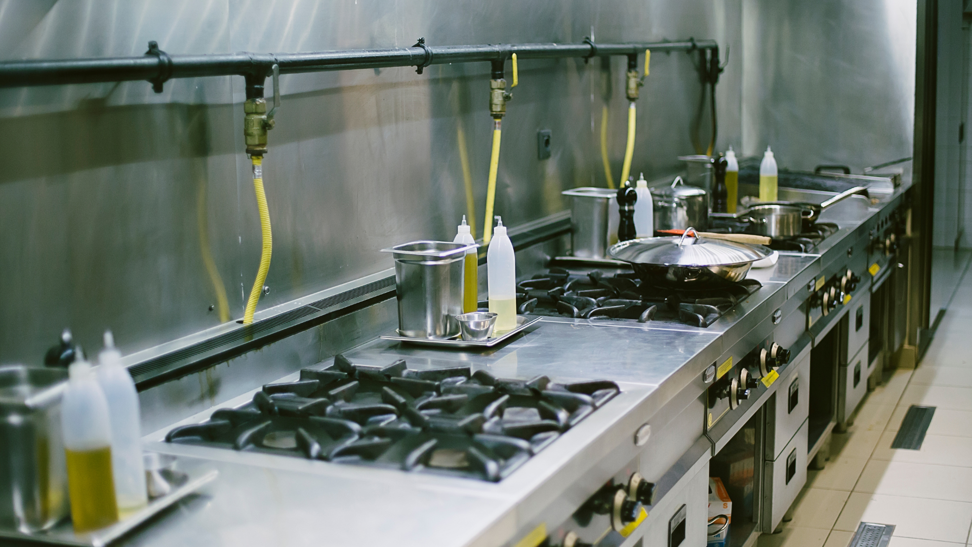 Commercial kitchen with stainless steel appliances and cooking equipment, including stoves and ovens.