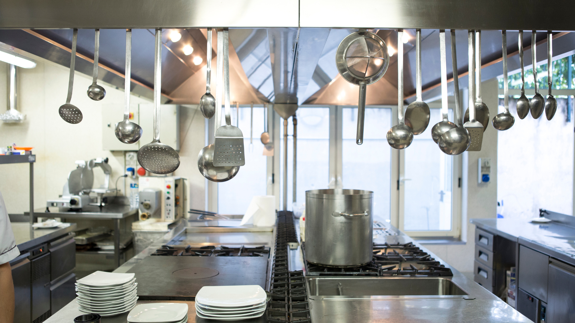 Commercial kitchen, stainless steel, equipment, utensils hanging, stove, cooking.