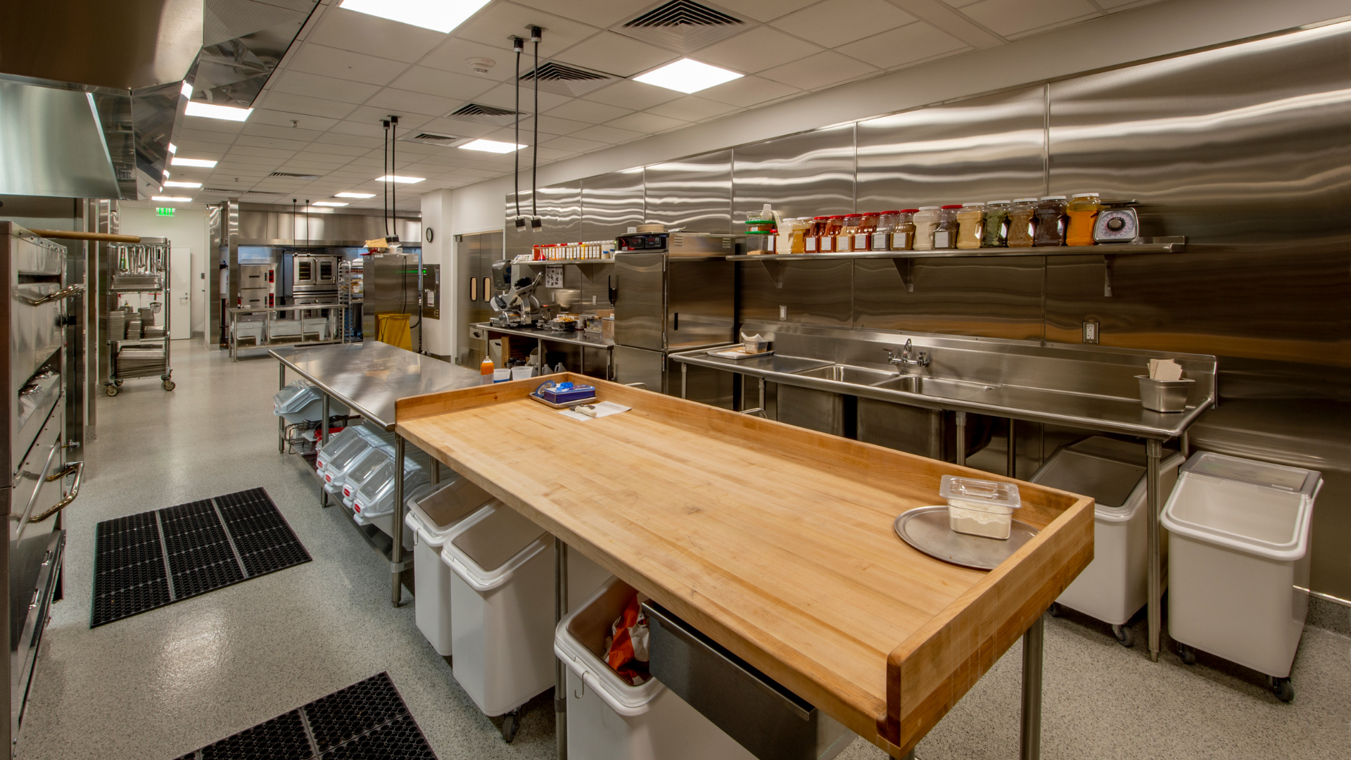 Commercial kitchen with stainless steel equipment and a large wooden counter.