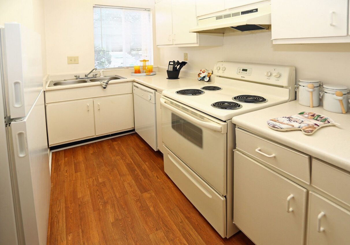 A kitchen with white cabinets , a stove , a refrigerator , and a sink.