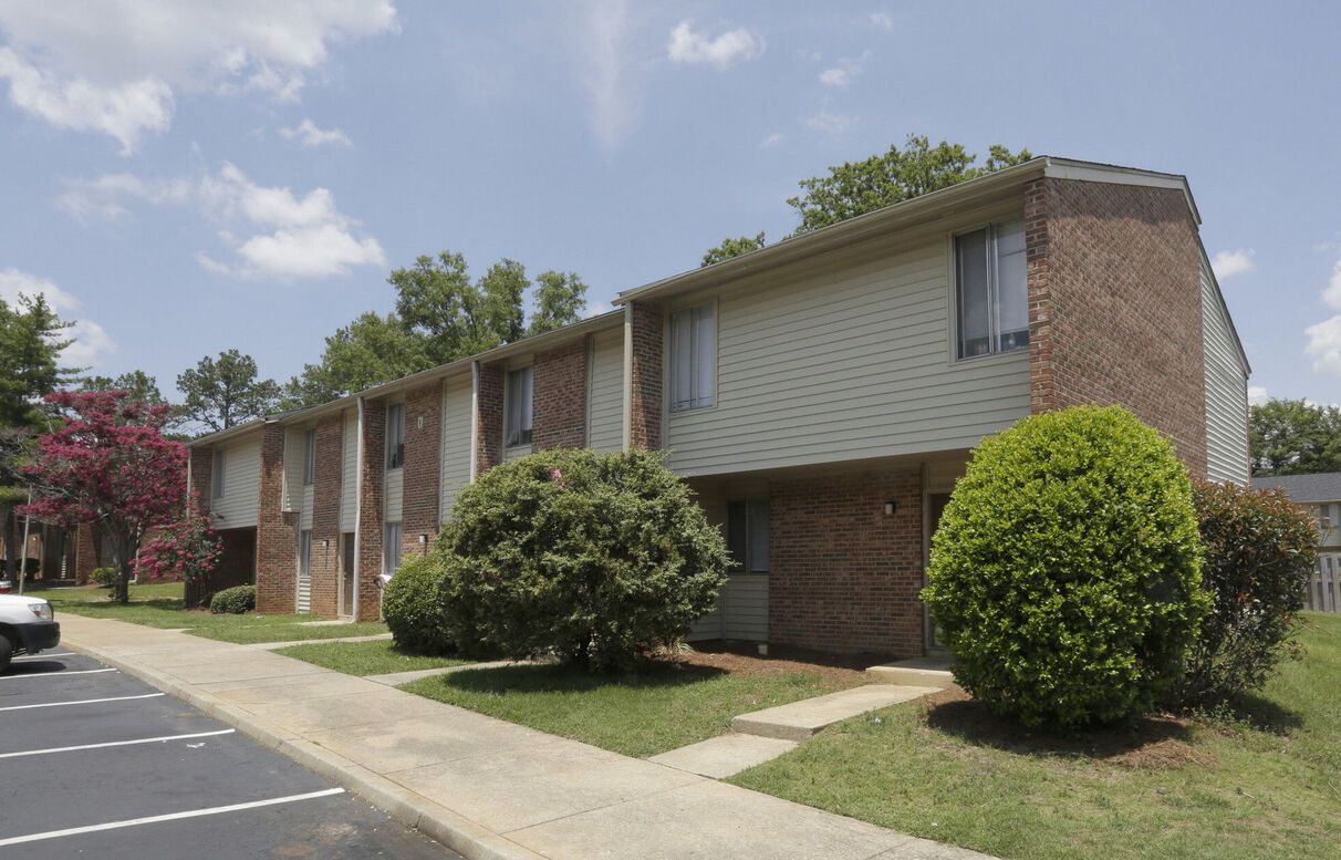 A white car is parked in front of a brick apartment building