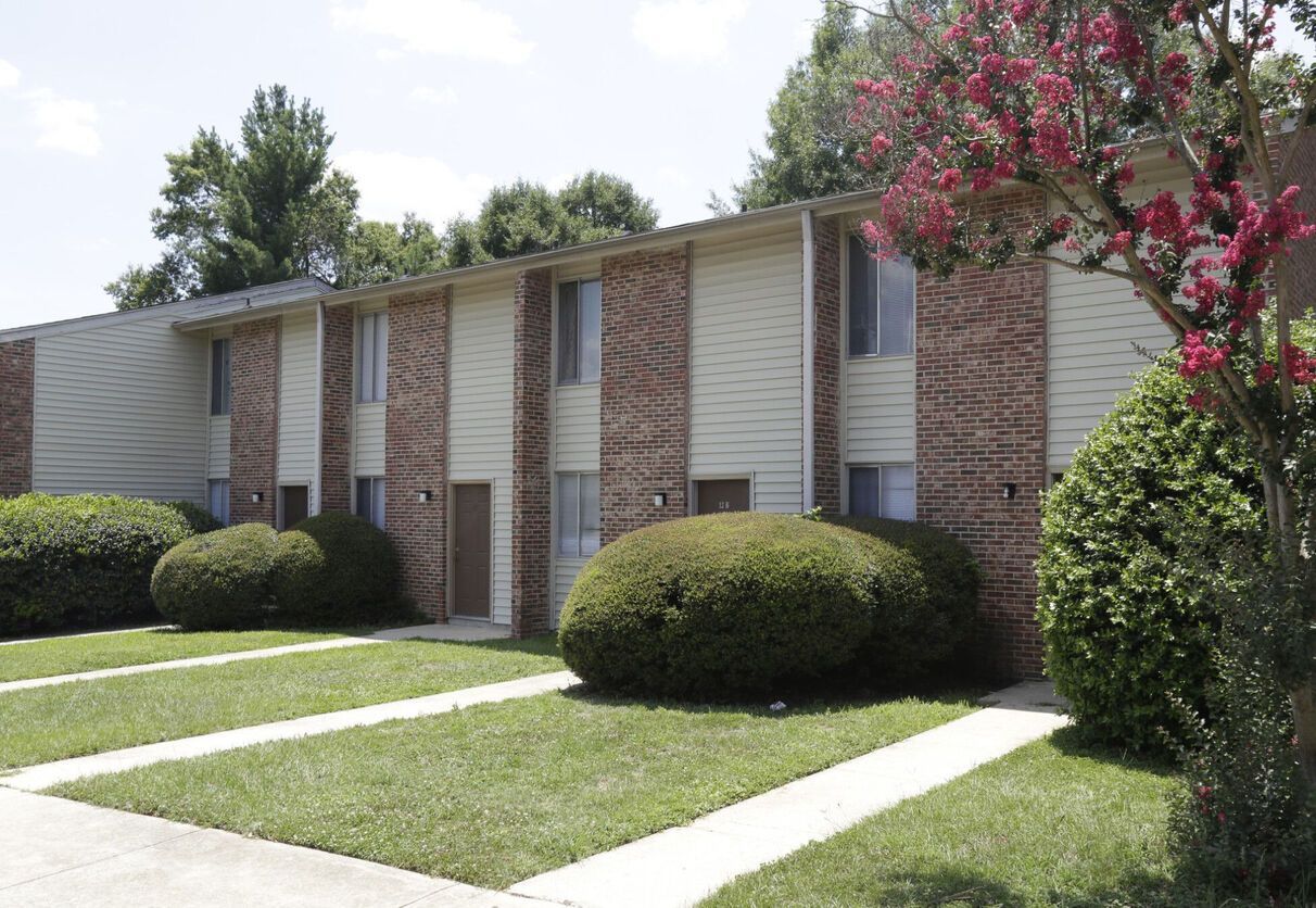A row of apartment buildings with a lush green lawn in front of them.