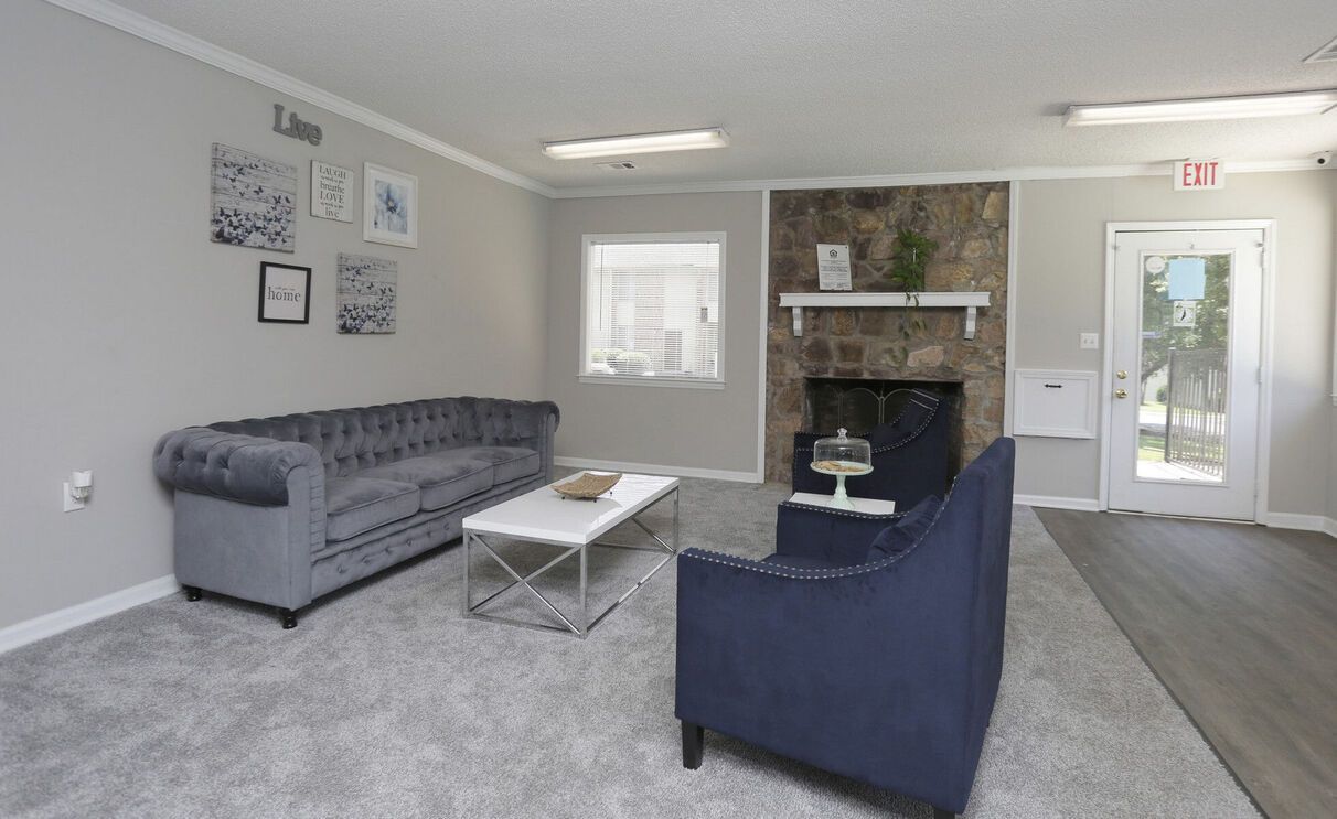 Living room with a gray sofa, blue armchair, stone fireplace, and art.
