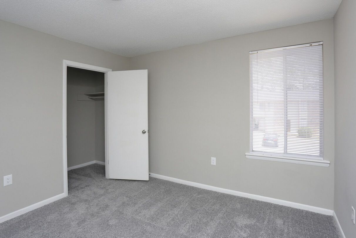 An empty bedroom with a closet and a window.