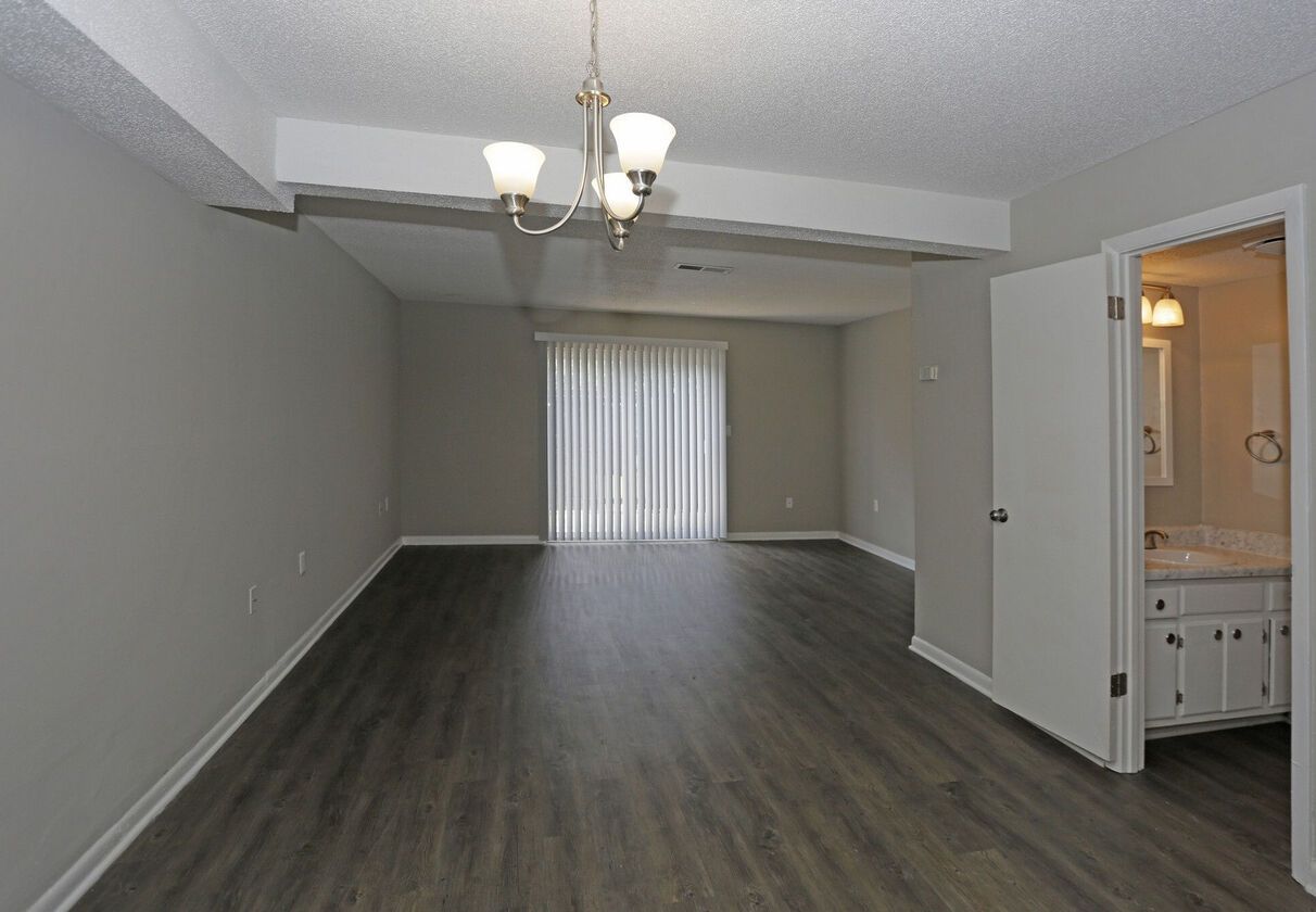 An empty living room with hardwood floors and a chandelier