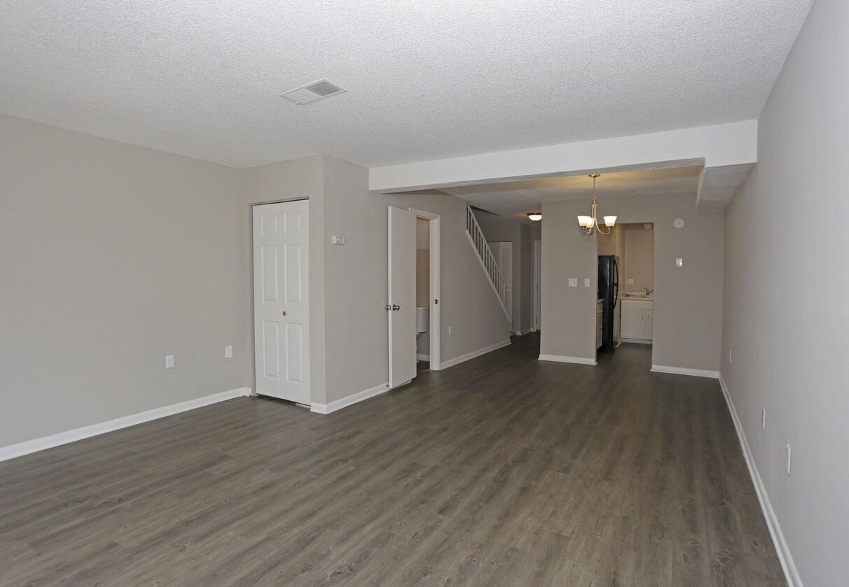 An empty living room with hardwood floors and white walls.