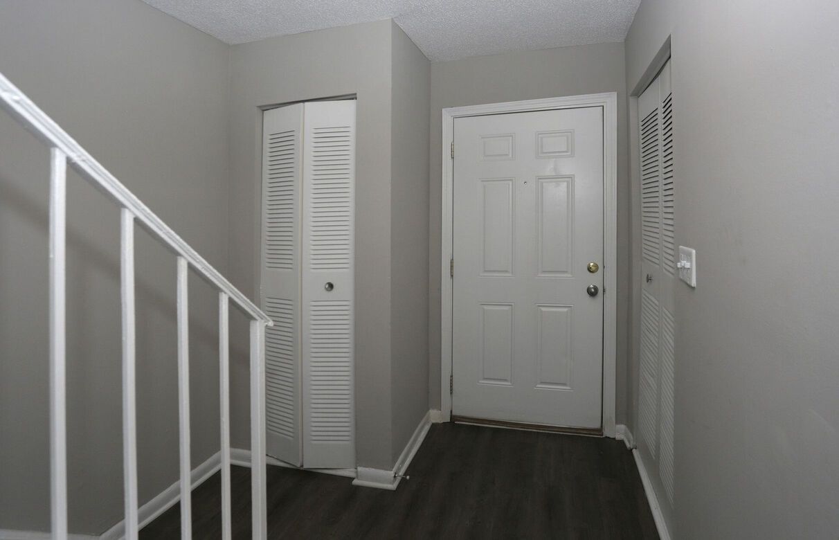 A hallway with a white railing and a white door