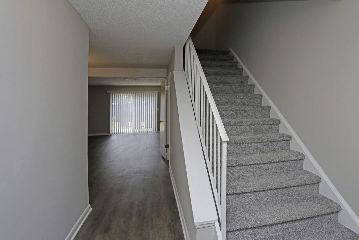 A hallway with stairs leading up to the second floor of a house.