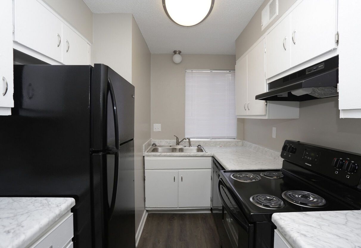 A kitchen with black appliances and white cabinets