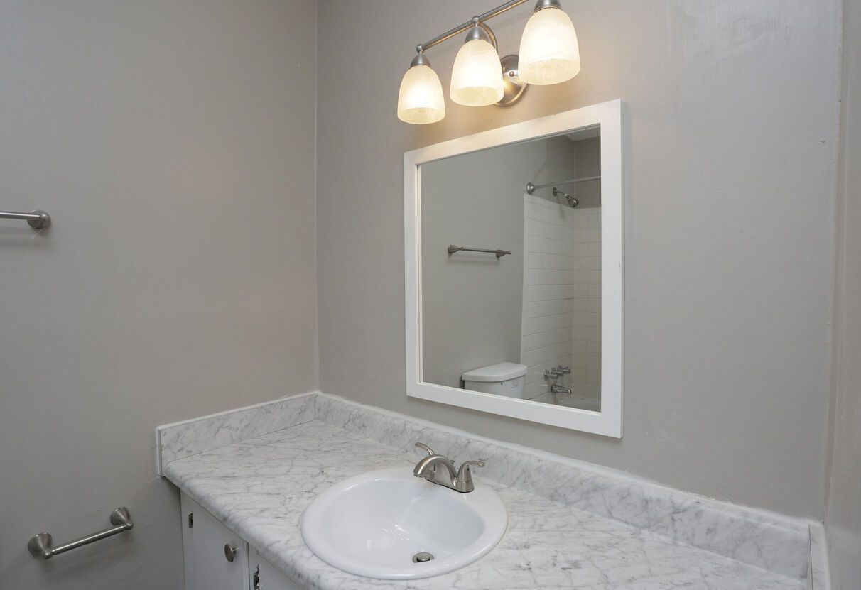 A bathroom with a sink , mirror , and toilet.