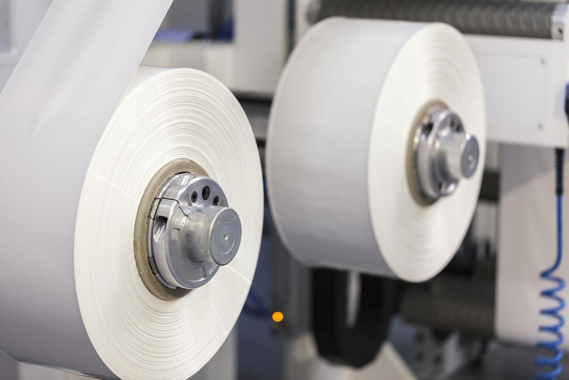 two rolls of paper are being rolled on a machine .