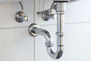 A close up of a plumbing pipe under a sink in a bathroom.