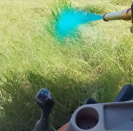 A Person Spraying Blue Paint on a Lawn With a Hose — CQ Rural Services In Bakers Creek, QLD