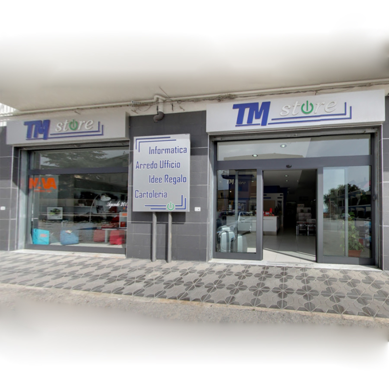 Vista esterna del TM Store, un negozio di computer e forniture per ufficio con facciata in vetro e porta aperta.