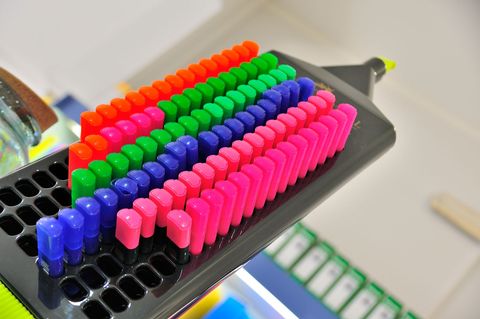 File di gomme colorate disposte su un evidenziatore nero, creando un effetto arcobaleno.