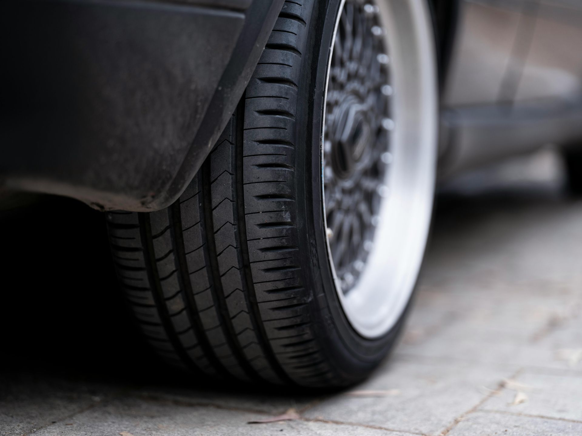 A close up of a car tire on a sidewalk.