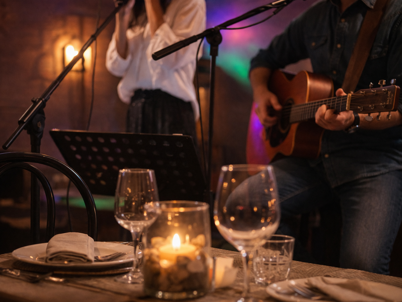 In un ristorante dall'atmosfera soffusa e illuminata a lume di candela, dei musicisti si esibiscono con chitarra e microfono.