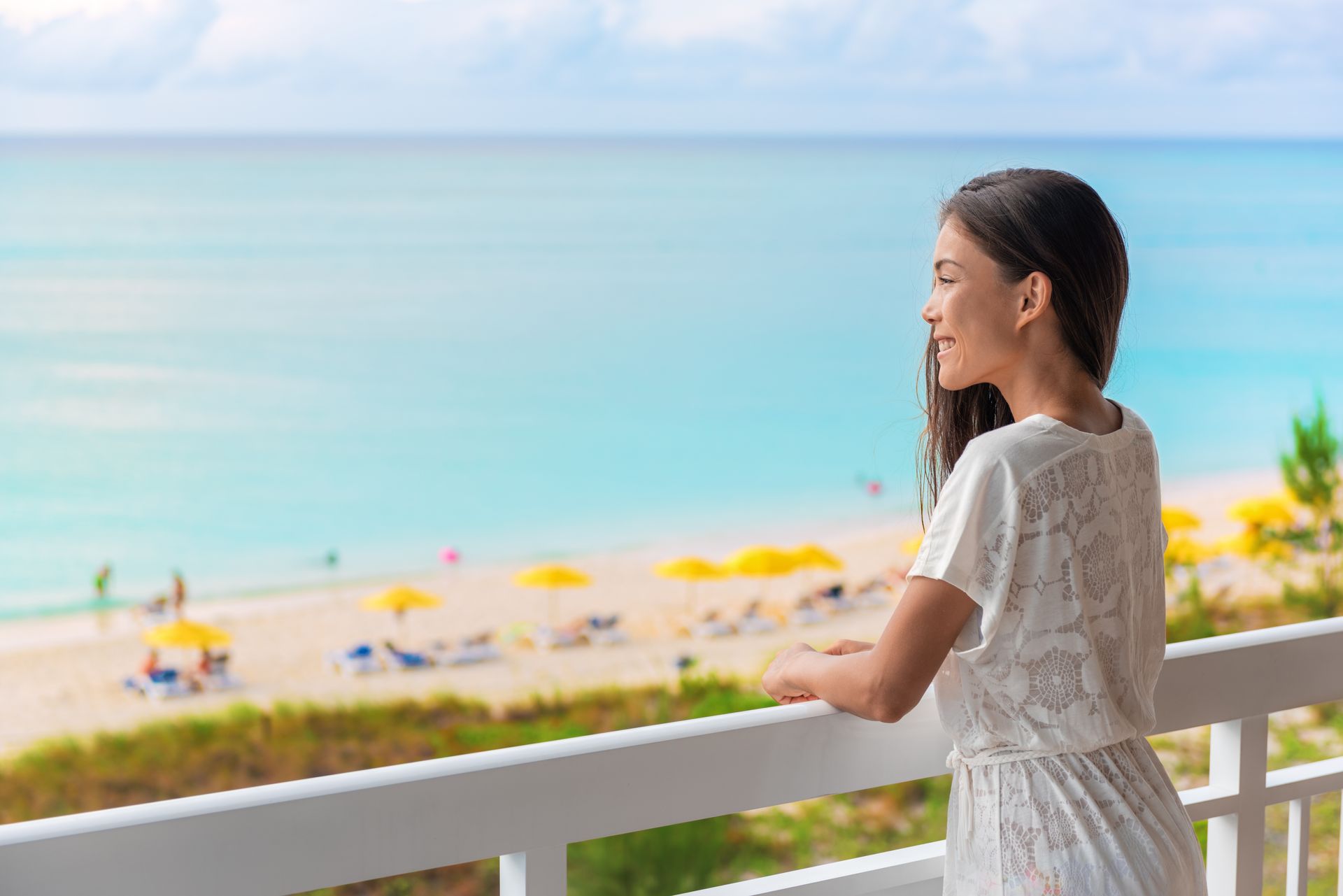 Resort vacation happy Asian woman tourist enjoying ocean view from beach front hotel room on Caribbean holidays.