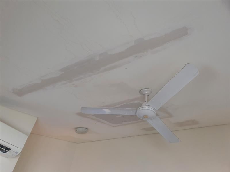 Ceiling with water damage and a fan. Gray water stains on white ceiling — Patch Plaster Paint in Johnston, NT