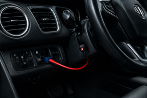 Car dashboard with a red charging cable plugged into the center console