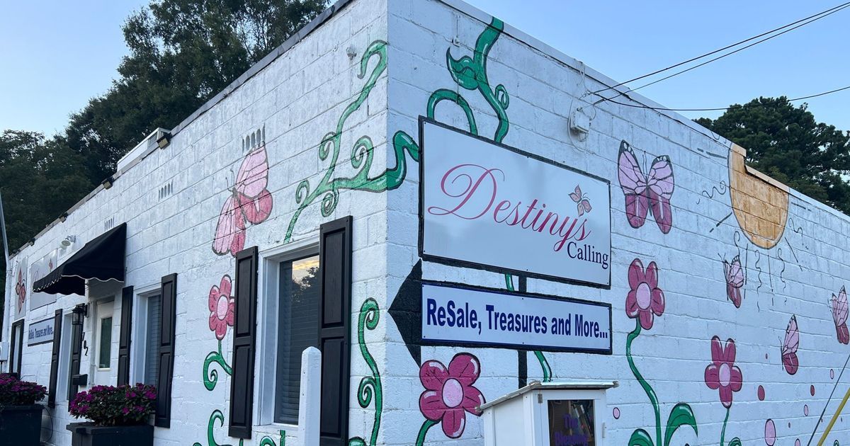 A white building painted with flowers and butterflies, featuring a sign for Destiny’s Closet ReSale, Treasures and More.