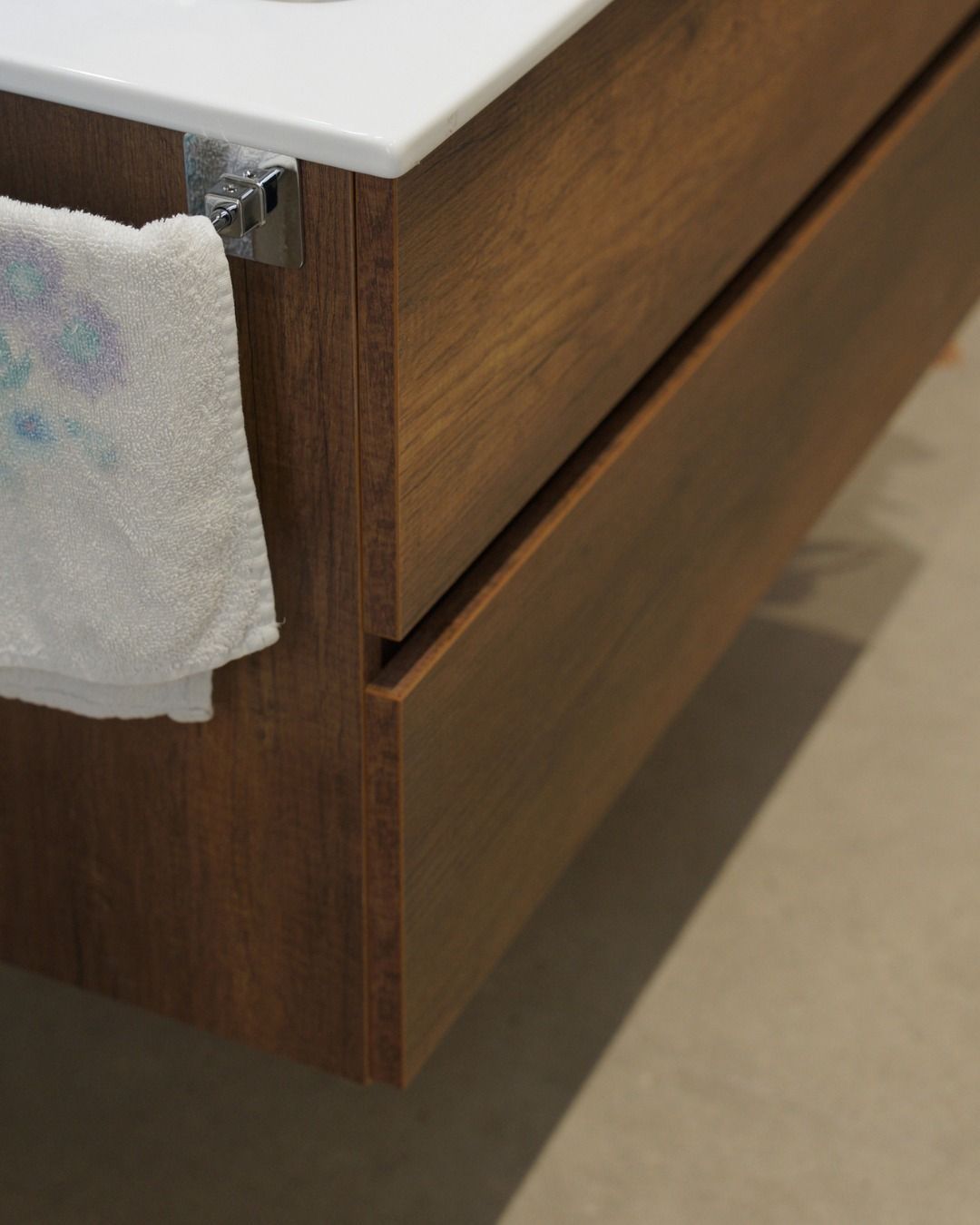 Cassetto di una cassettiera in legno con un panno bianco drappeggiato su un angolo, su un tappeto beige.