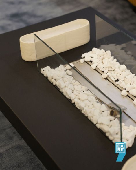 Modello da tavolo nero con rocce bianche, un blocco color crema e pannelli a specchio che circondano un canale centrale.
