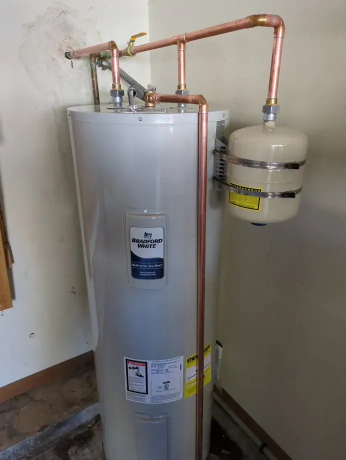 A white water heater with copper pipes attached to it