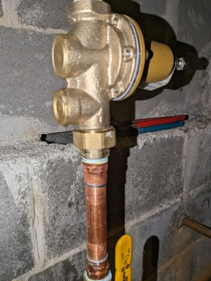 A brass valve is attached to a copper pipe.