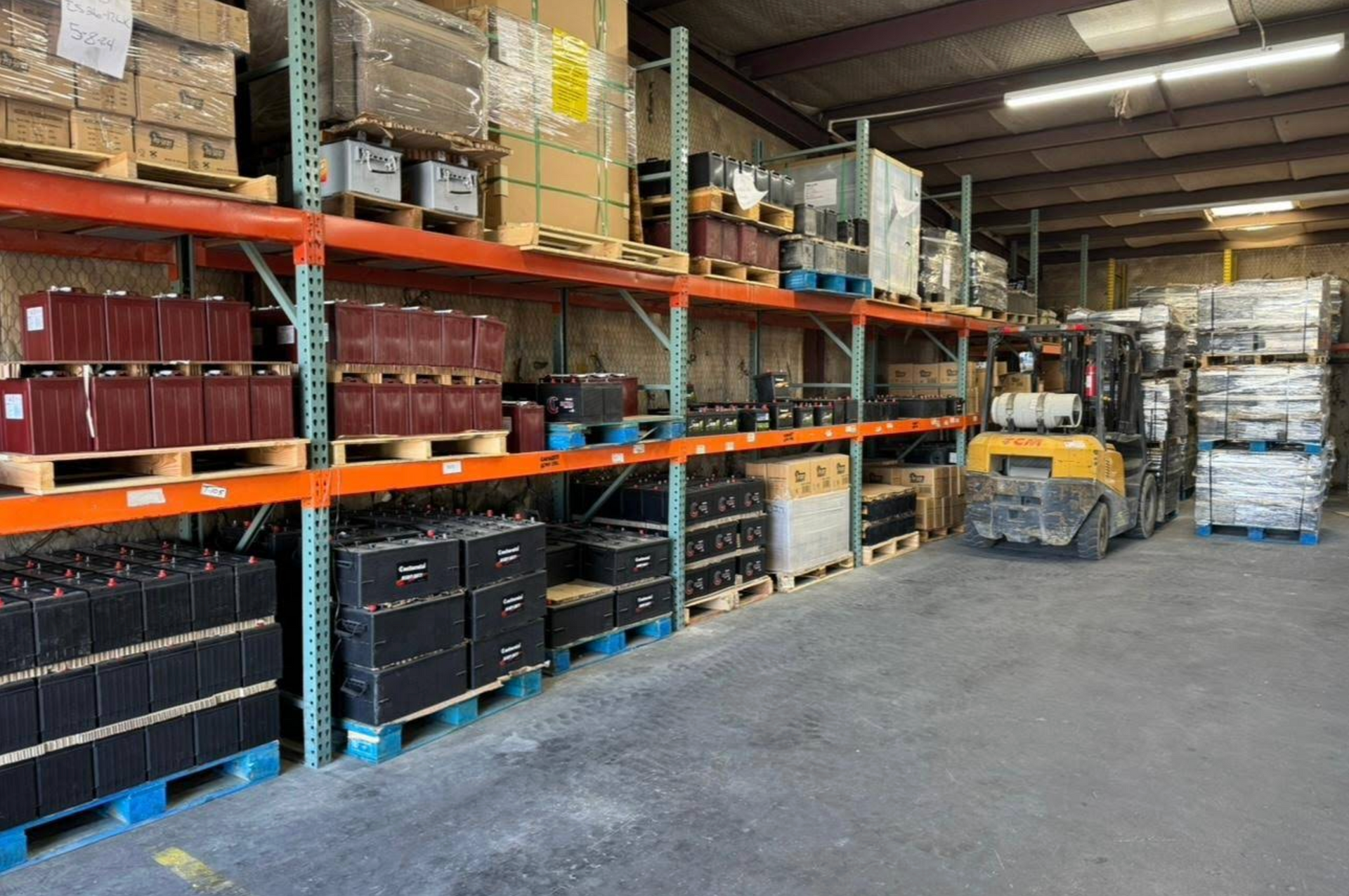A warehouse filled with lots of batteries and a forklift.