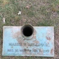A flat, rectangular bronze grave marker for Massie T. Mullinax (1909–1959) featuring a central cylindrical vase.