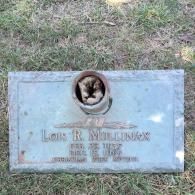 A granite grave marker for Lon R. Mullinax with a central metal flower vase containing a small, furry animal.