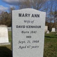 A light gray granite headstone in a cemetery reads: 