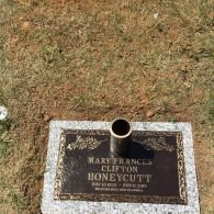 A flat bronze grave marker on a granite base for Mary Frances Clifton Honeycutt, with a metal flower vase in the center.