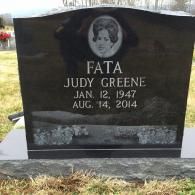 A black granite headstone for Judy Greene Fata, featuring a portrait etching, dates Jan. 12, 1947, and Aug. 14, 2014.