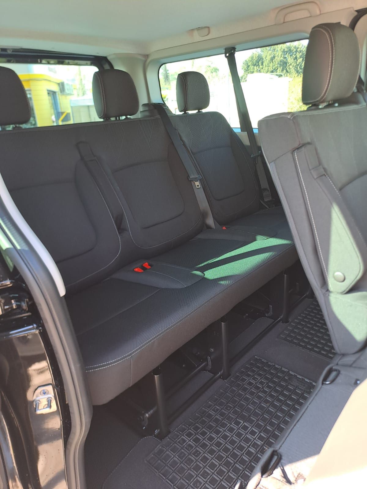 Vista interna di un minivan nero con tre sedili neri nella fila posteriore.