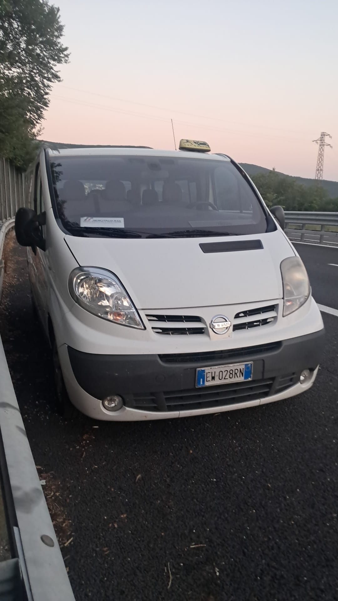 Un taxi Nissan bianco parcheggiato sul ciglio della strada.