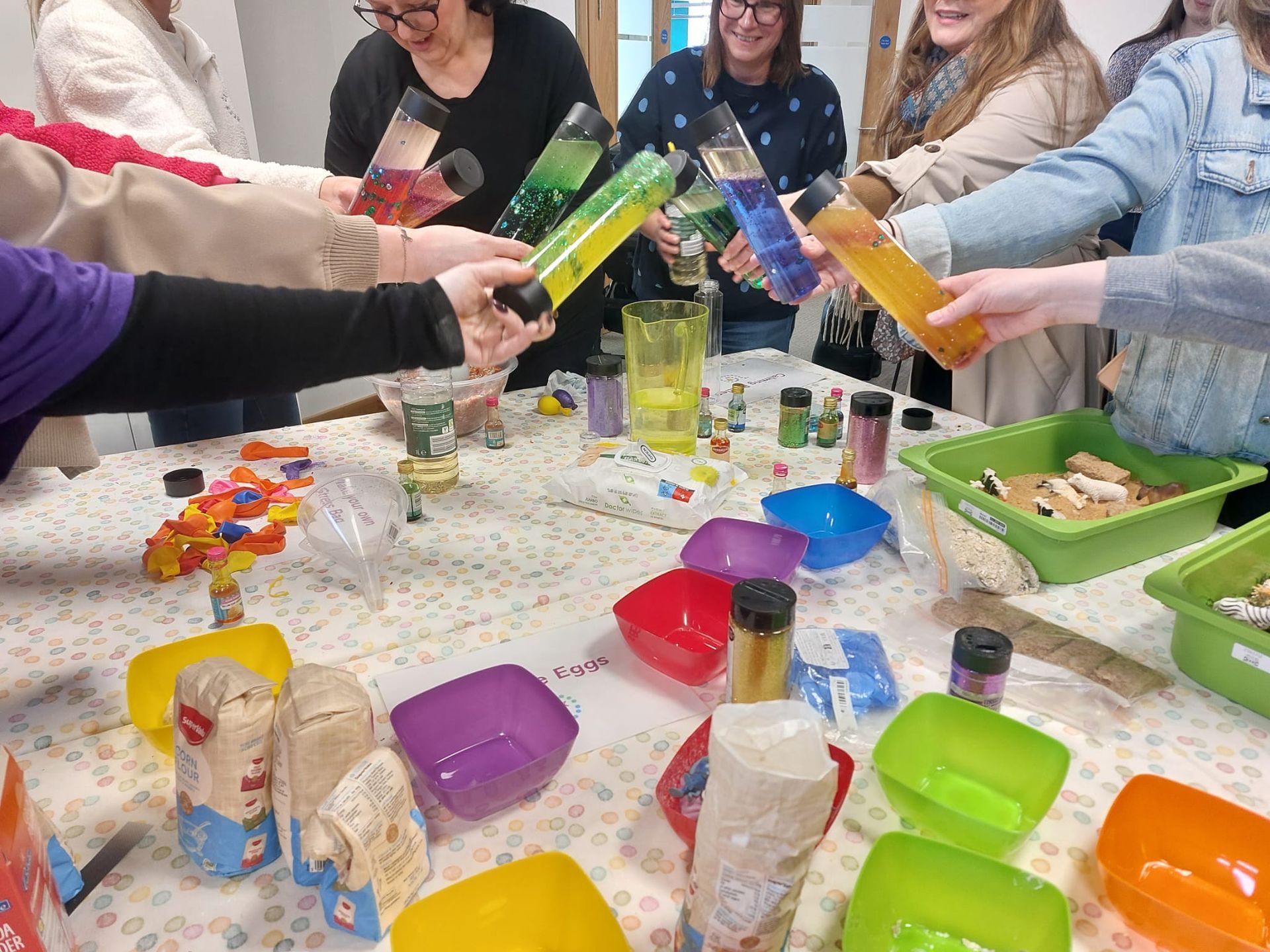 Women are holding bottles with colorful liquid