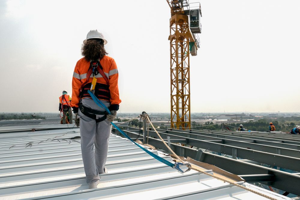 Construction Worker on a Rooftop Wearing Safety Harness — Vision Roofing Fascia & Gutter in Hervey Bay, QLD
