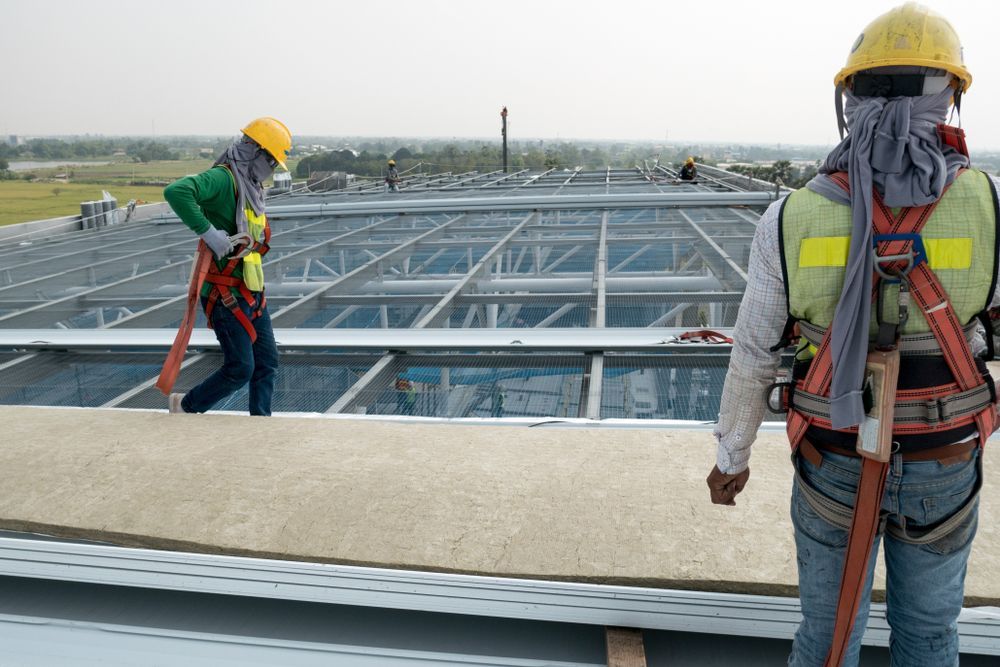 Workers Wearing Safety Harnesses and Hard Hats on a Rooftop — Vision Roofing Fascia & Gutter in Hervey Bay, QLD