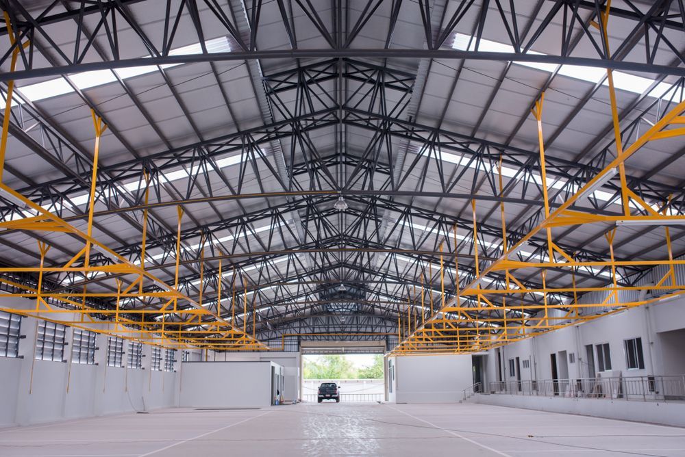 Inside a Large, Empty Metal Building With a High Truss Roof — Vision Roofing Fascia & Gutter in Hervey Bay, QLD