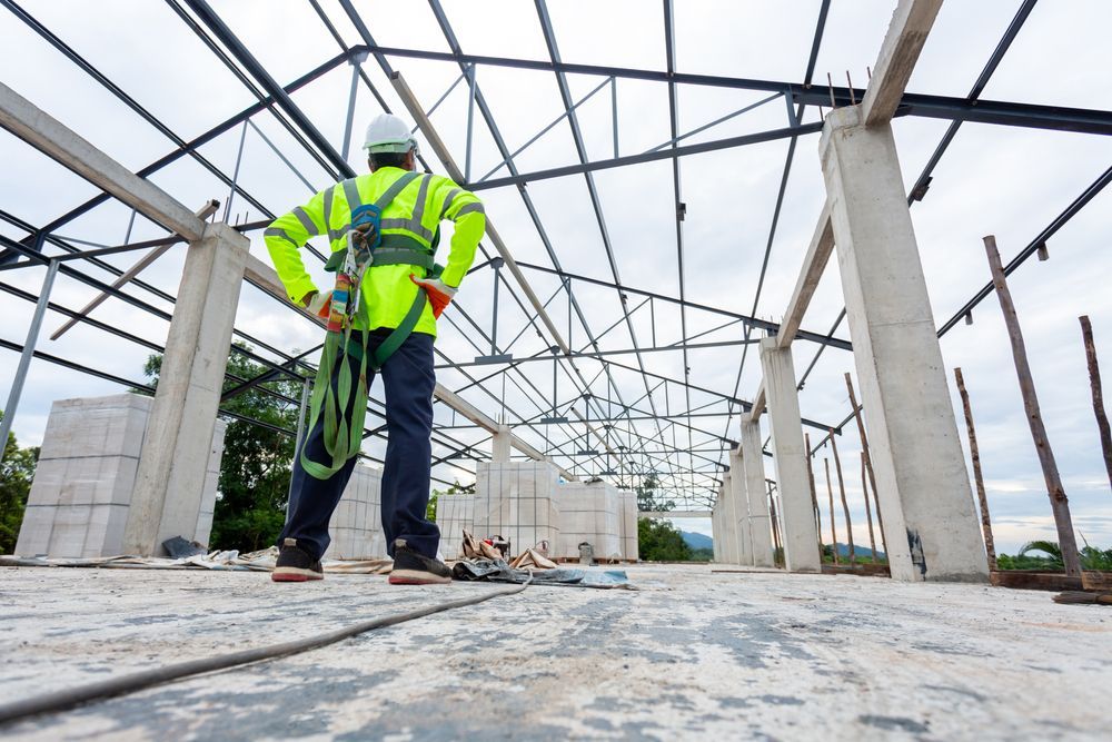 Worker Wearing Safety Gear Surveys the Structural Frame of a Building — Vision Roofing Fascia & Gutter in Burrum Heads, QLD