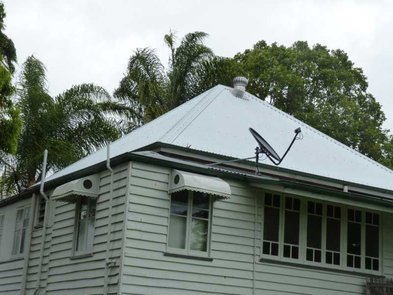 White Clapboard House With Metal Roof, Satellite Dish, and Awnings — Vision Roofing Fascia & Gutter in Hervey Bay, QLD