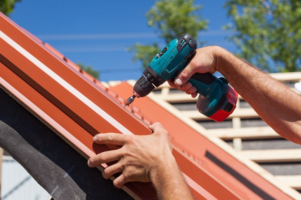 Person Using a Drill to Install Metal Roofing Material — Vision Roofing Fascia & Gutter in Hervey Bay, QLD